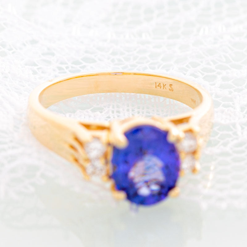 Blue Oval Tanzanite ring with diamonds in 14k yellow gold.